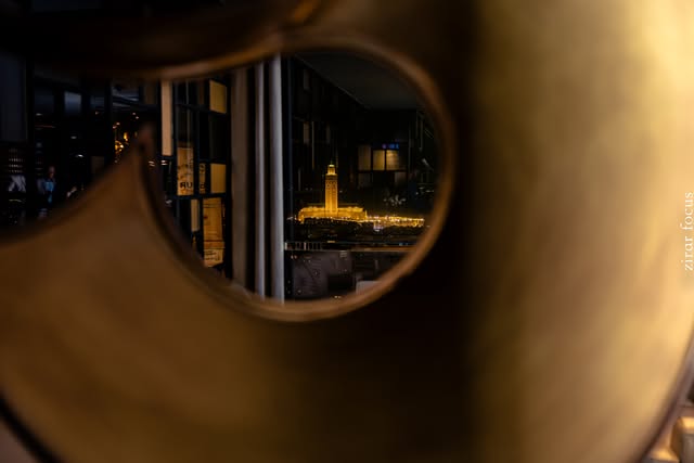 Architecture éclairée de nuit vue à travers une forme métallique
