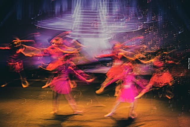Danseuses en mouvement sous des lumières roses et orangées