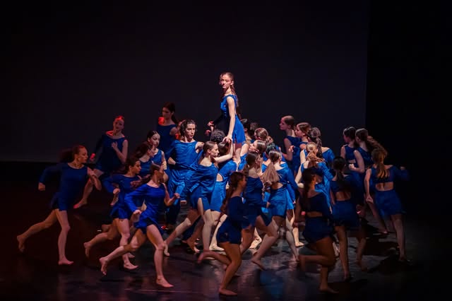 Ensemble de danseurs vêtus de bleu sur une scène
